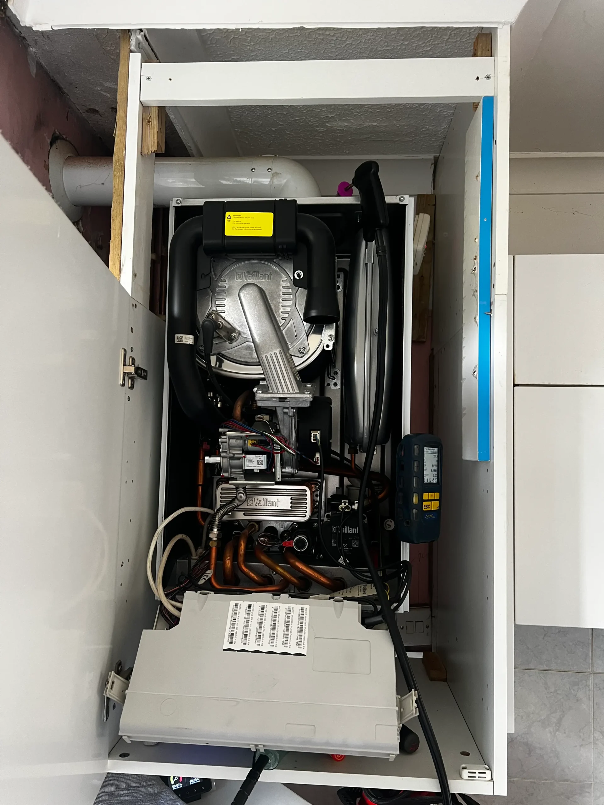 Vaillant boiler with the cover off during a service in Harrow, with a flue gas analyser connected