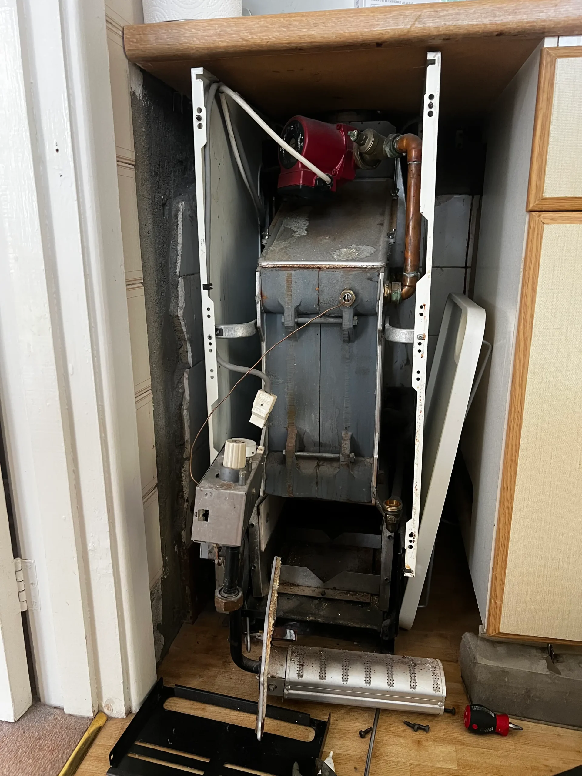 Gas Safe engineer repairing a boiler in Harrow, with the burner removed